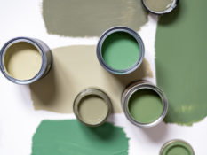 Tiny sample paint cans during house renovation, process of choosing paint for the walls, different green colors, color charts on background